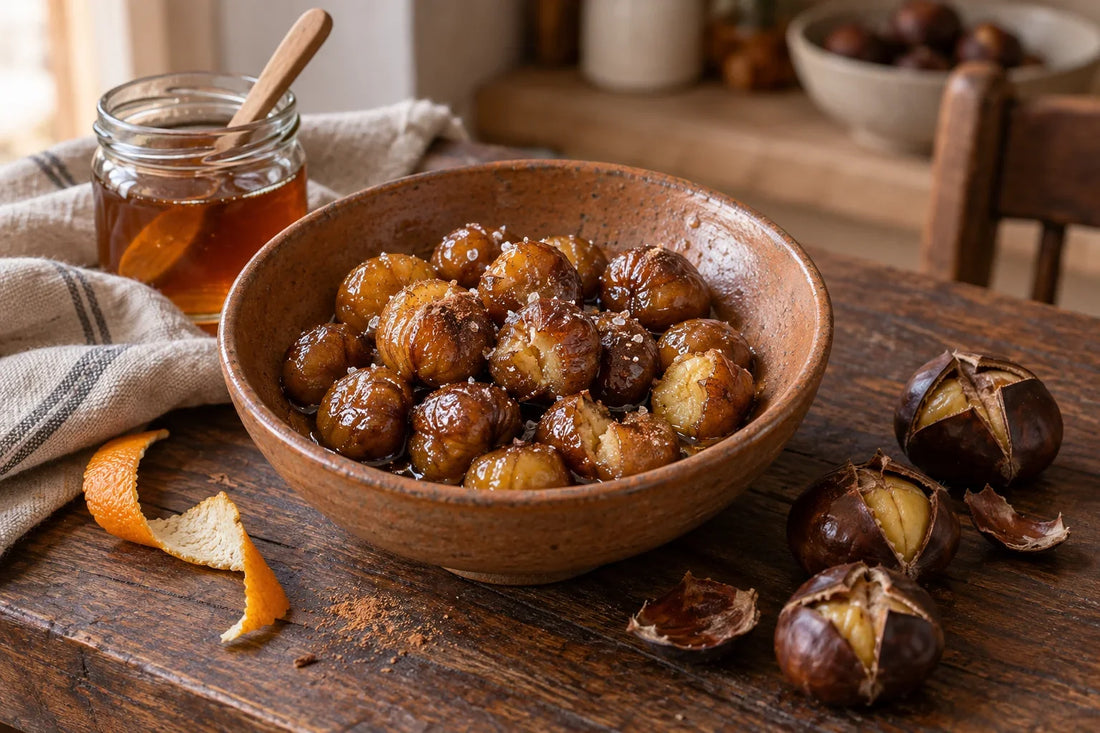 Cuenco de castañas peladas y glaseadas con miel, junto a castañas asadas con la cáscara abierta y un tarro de miel.