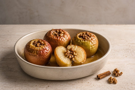 Cuatro manzanas asadas con miel, canela y nueces en una fuente de cerámica