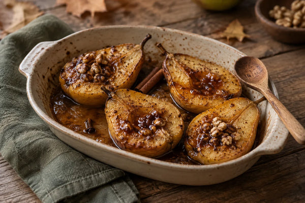 Peras al horno con glaseado de miel, canela y clavo, en una fuente con nueces troceadas