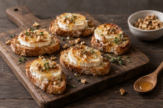 Tostas de pan con queso de cabra gratinado, miel y nueces troceadas, en una tabla de madera