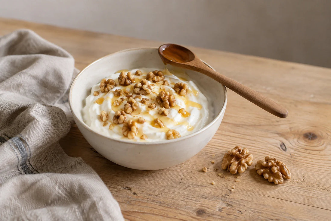 Bol de yogur griego con nueces troceadas y miel con cuchara de madera